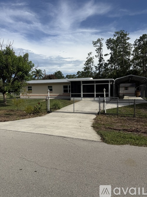 A house with a driveway and a fence in front of it.