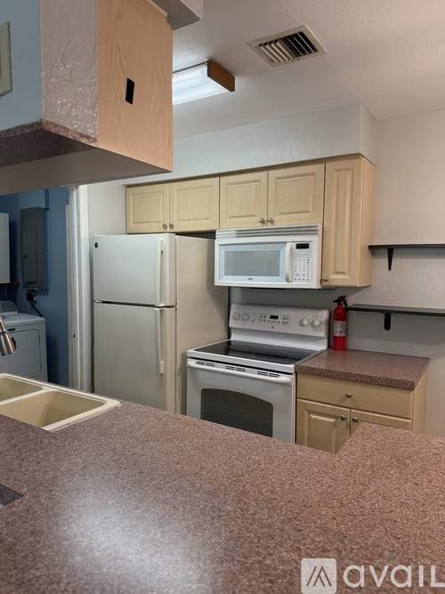 A kitchen with a refrigerator, microwave, oven, and sink.