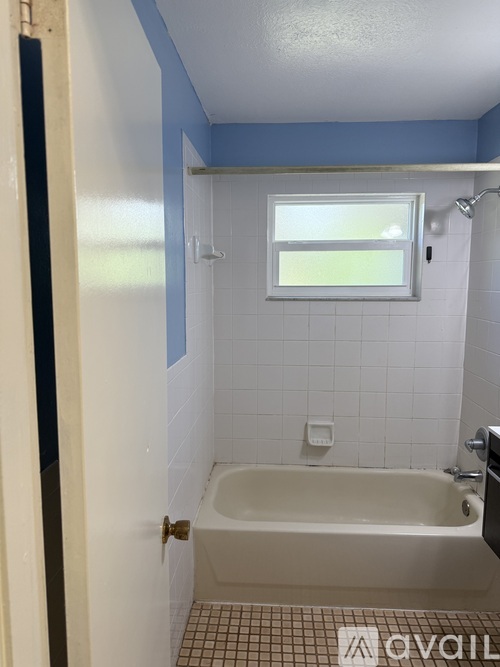 A small bathroom with a white tub and a window.