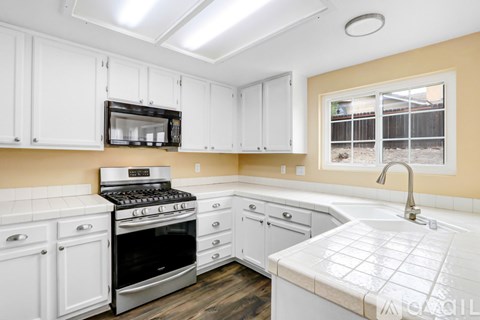 A kitchen with white cabinets and a black stove top oven.
