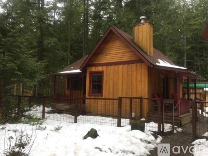A wooden cabin with a brown roof and a brown fence in the snow.