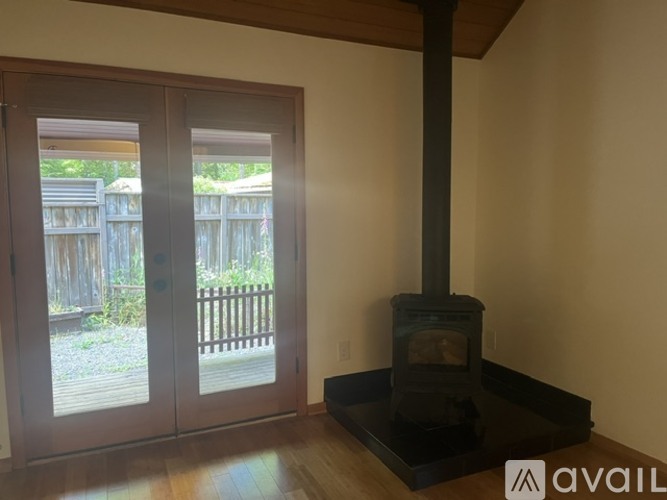 A wood stove is in a black hearth in a room with a wood deck outside.