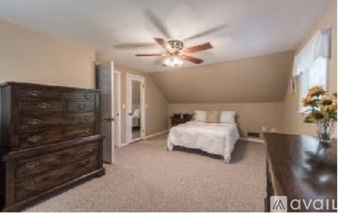 A bedroom with a bed, dresser, and ceiling fan.