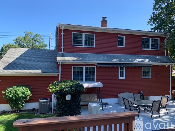 A red house with a white roof and a wooden deck.