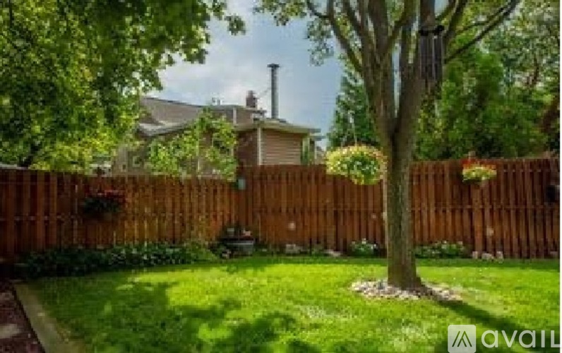 A backyard with a fence, a tree, and a house in the background.