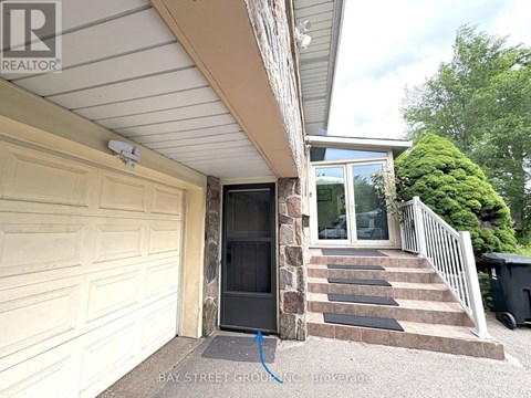 A house with a garage door and steps leading to a glass door entrance.