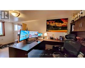 A home office with a desk, computer, and a painting on the wall.