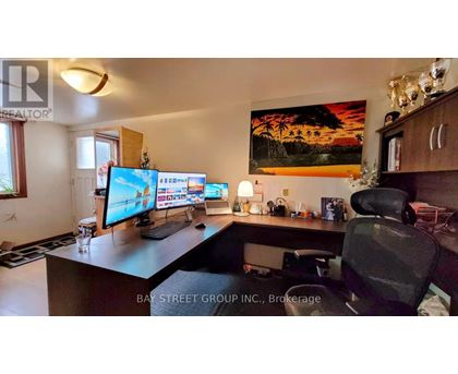 A home office with a desk, computer, and a painting on the wall.