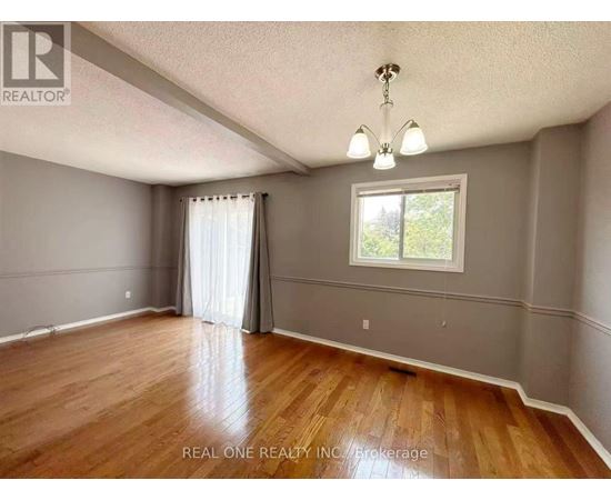 A room with wooden floors and a window with white curtains.
