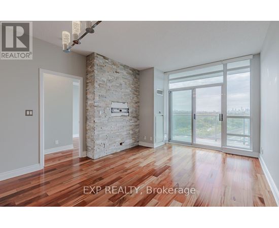 A room with wooden floors and a stone wall with a glass door leading outside.
