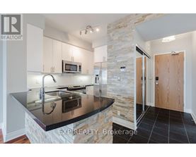 A kitchen with a stone column and a black counter top.