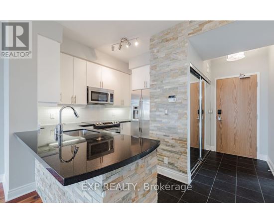 A kitchen with a stone column and a black counter top.