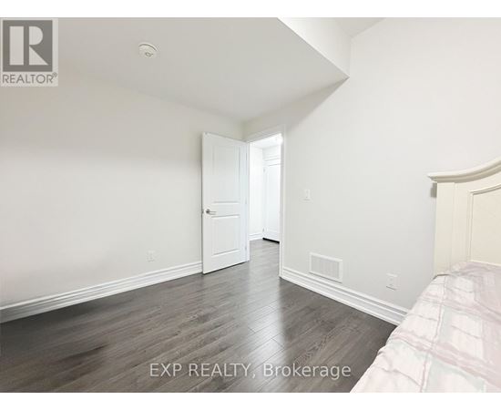 A bedroom with a bed on the right side and a doorway leading to another room.