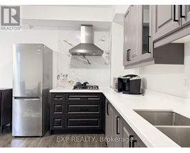 A kitchen with a stainless steel refrigerator and a marble backsplash.