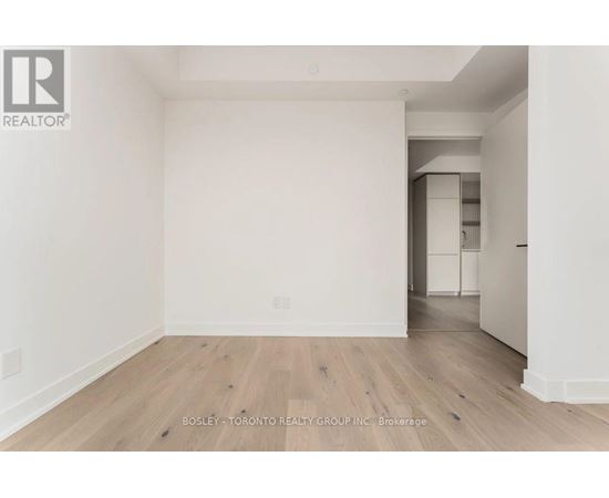 A spacious room with wooden flooring and white walls, part of a property by the Bosley - Toronto Realty Group Inc.