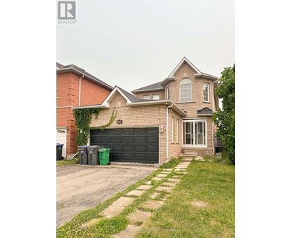A house with a grey garage door and a brick wall.
