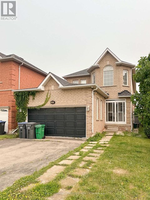 A house with a grey garage door and a brick wall.