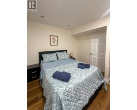 A bedroom with a bed, pillows, and a picture on the wall.
