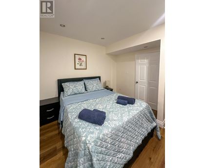 A bedroom with a bed, pillows, and a picture on the wall.
