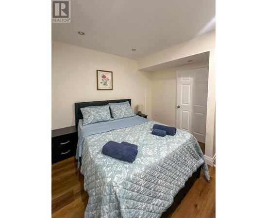 A bedroom with a bed, pillows, and a picture on the wall.