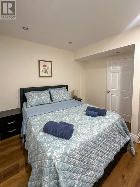 A bedroom with a bed, pillows, and a picture on the wall.