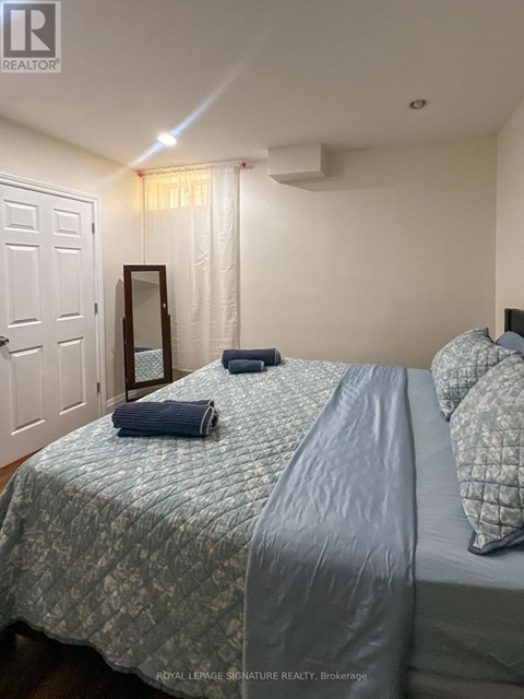 A bedroom with a bed, pillows, and a mirror.