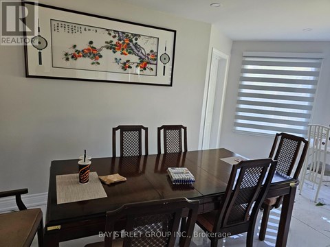 A dining room with a table set for two and a framed picture on the wall.