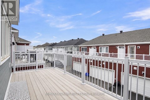 A balcony with a white railing and a red building in the background.