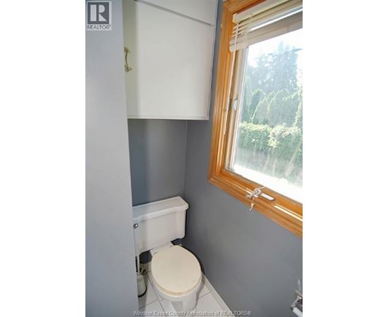 A white toilet in a small bathroom with a window.