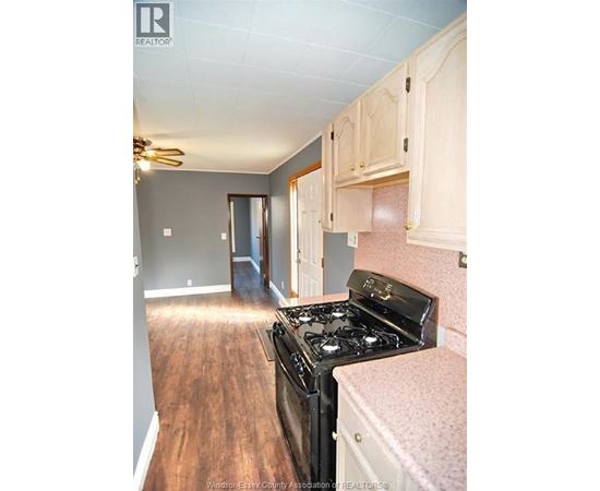 A kitchen with a black stove top oven and wooden floors.
