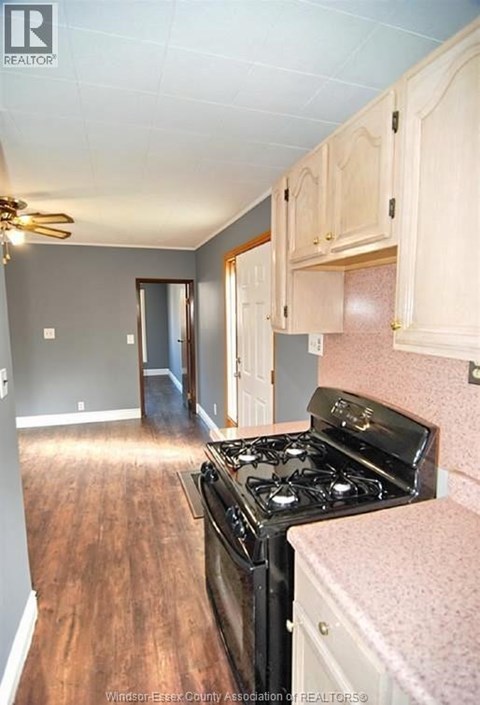 A kitchen with a black stove top oven and wooden floors.
