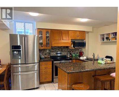 A kitchen with a refrigerator, sink, and cabinets.