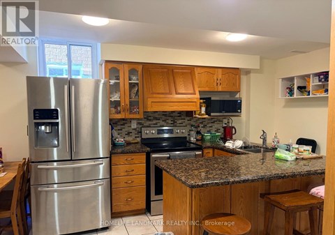 A kitchen with a refrigerator, sink, and cabinets.