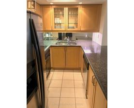 A kitchen with wooden cabinets and a black refrigerator.