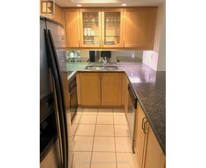 A kitchen with wooden cabinets and a black refrigerator.