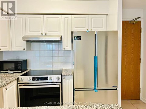 A kitchen with white cabinets and a black microwave above the stove.