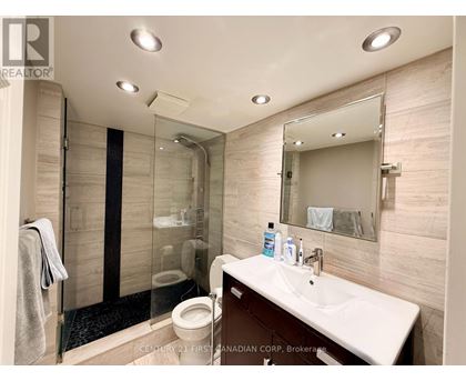 A bathroom with a toilet, sink, mirror, and shower.