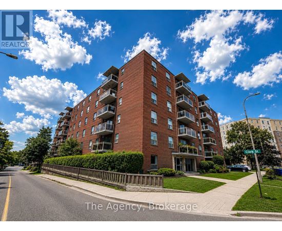 A tall red brick apartment building with balconies on the upper floors.