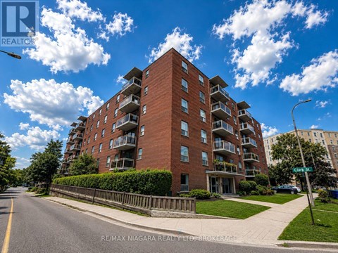 A tall red brick apartment building with balconies on the upper floors.