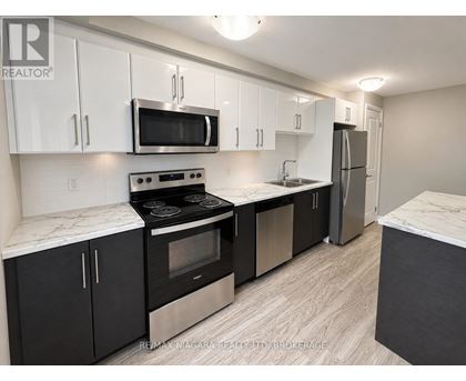 A kitchen with black cabinets and stainless steel appliances.
