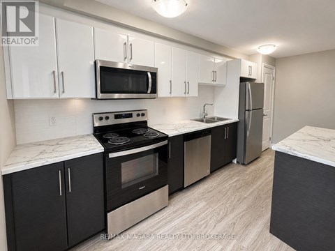 A kitchen with black cabinets and stainless steel appliances.