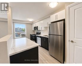 A kitchen with a refrigerator, microwave, and oven.