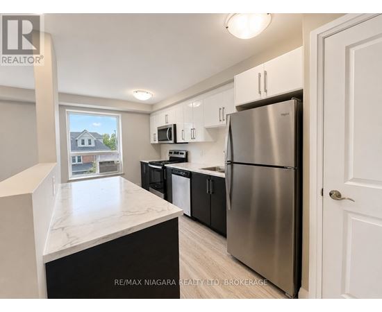A kitchen with a refrigerator, microwave, and oven.