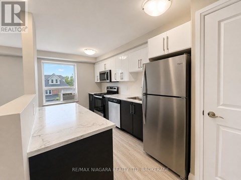 A kitchen with a refrigerator, microwave, and oven.