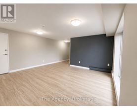A spacious room with wooden flooring and a large window.