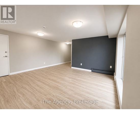 A spacious room with wooden flooring and a large window.