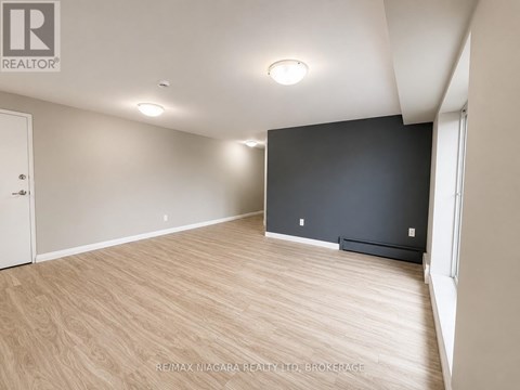A spacious room with wooden flooring and a large window.