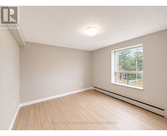 A room with a window and a wooden floor.