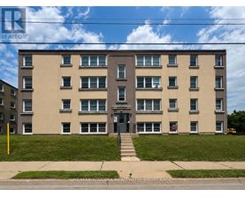 A large apartment building with a green lawn in front.