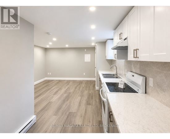 A kitchen with a white counter top and wooden floors.